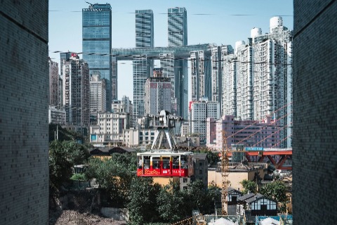 Visitors are riding the cableway, with the cityscape of Chongqing in the background.