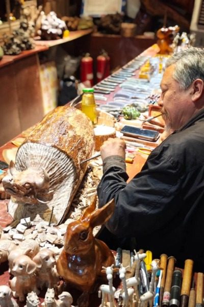 In Ciqikou Ancient Town, Chongqing, a Chinese artisan is carving wood.