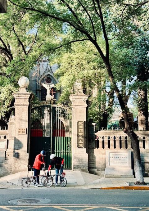 Two cyclists are resting in front of a former embassy building on Dongjiaomin Lane in Beijing.