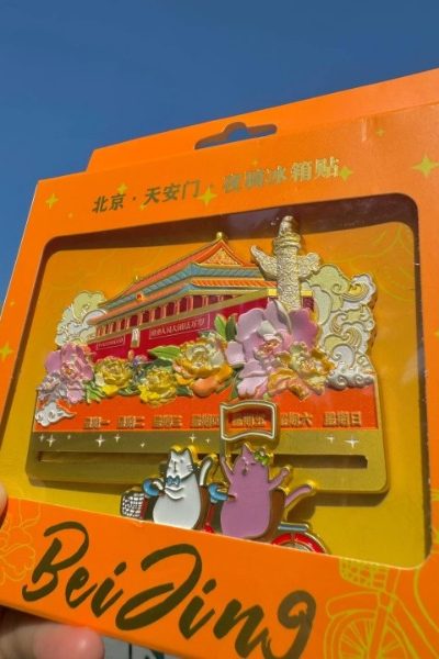 A Tiananmen-shaped fridge magnet, with two cats riding bicycles nearby.