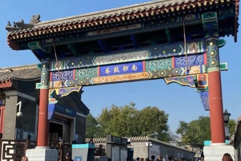 Tourists are walking through the entrance of Nanluoguxiang, with its striking red columns.