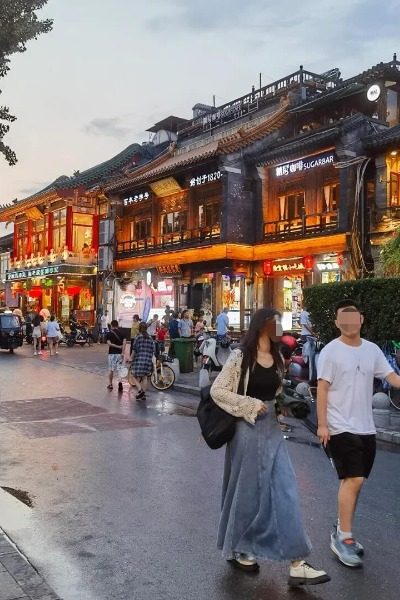 Visitors are taking a stroll along the Houhai Bar Street.