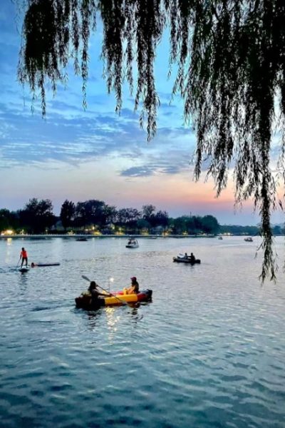 In the evening at Shichahai, visitors are kayaking on the lake.