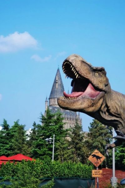 A dinosaur model stands at the entrance of the Jurassic World theme park.