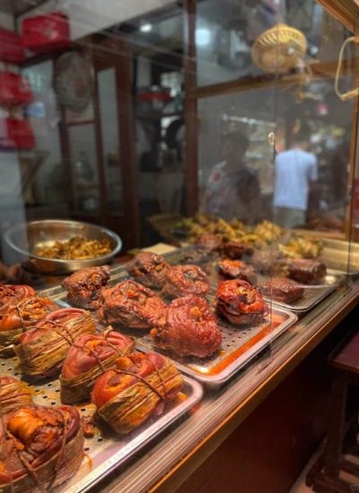 The restaurant's window showcases a variety of traditional Chinese dishes, including braised pig's trotters.