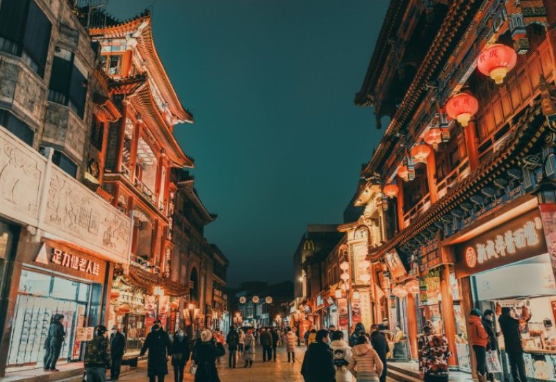 At night, many tourists in Beijing explore Qianmen Street and enjoy Beijing cuisine.