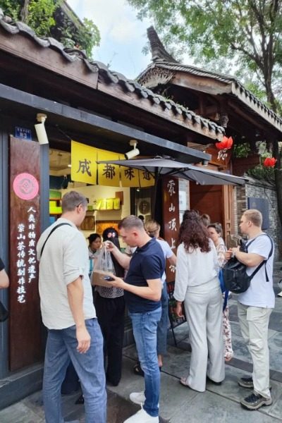 Foreign tourists are buying Chengdu snacks in Kuan Zhai Alley.