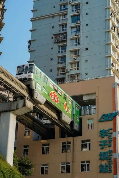 The subway train is emerging from within the residential buildings at Liziba Metro Station.