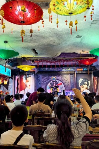 Tourists watching Sichuan opera face-changing in Chengdu Kuanzhai Alley.