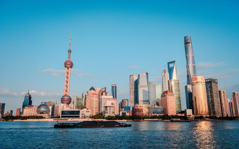 The cargo ships on the Huangpu River have the bustling Lujiazui of Shanghai in the background.