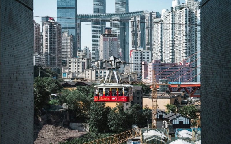 Tourists are riding the Yangtze River Cableway in Chongqing, with the city skyline in the background.