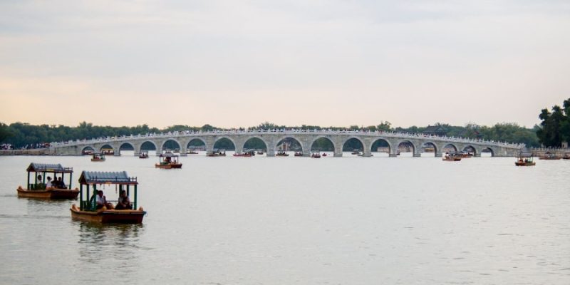 Tourists enjoy the Seventeen Arch Bridge while rowing boats in the Summer Palace.