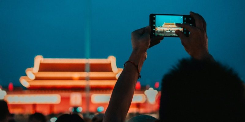 Tourists traveling to Beijing raise their phones to capture the process of the flag-raising at dawn.