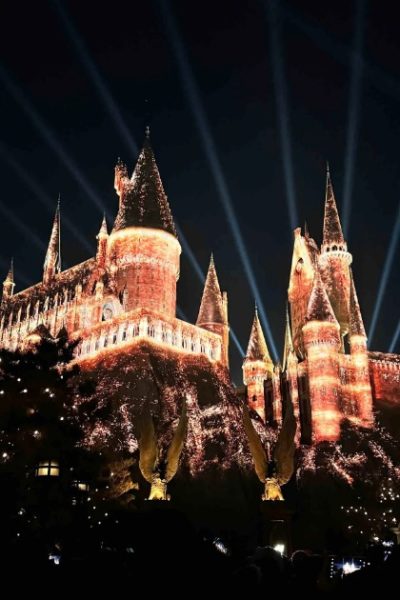 The castle in the Harry Potter Wizarding World is illuminated with a light show at night.