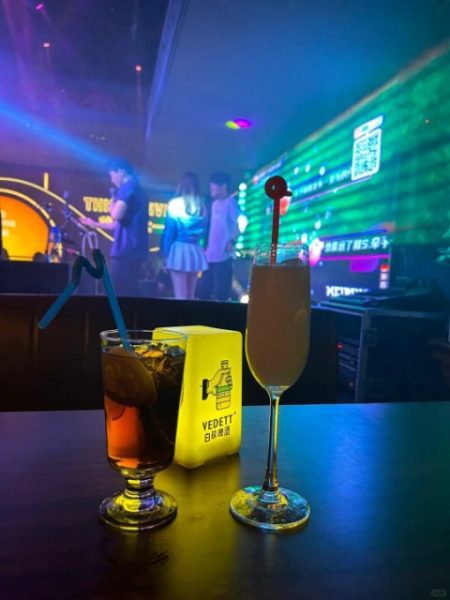 Tourists sit in a Beijing bar, sipping cocktails while enjoying a performance by the singer on stage.