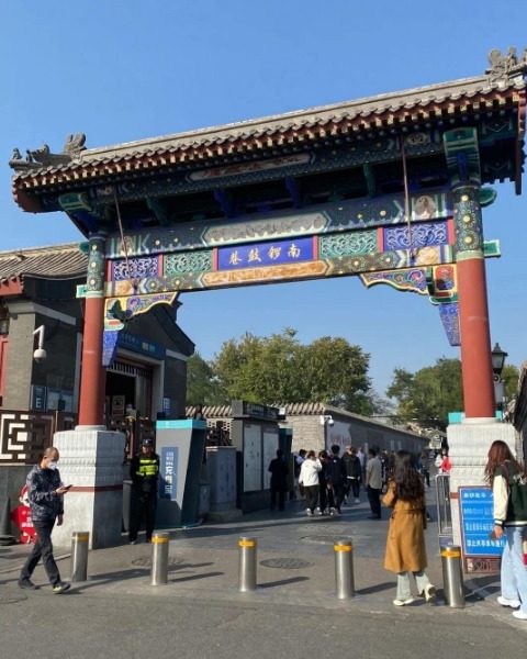 Tourists are walking through the entrance of Nanluoguxiang, with its striking red columns.